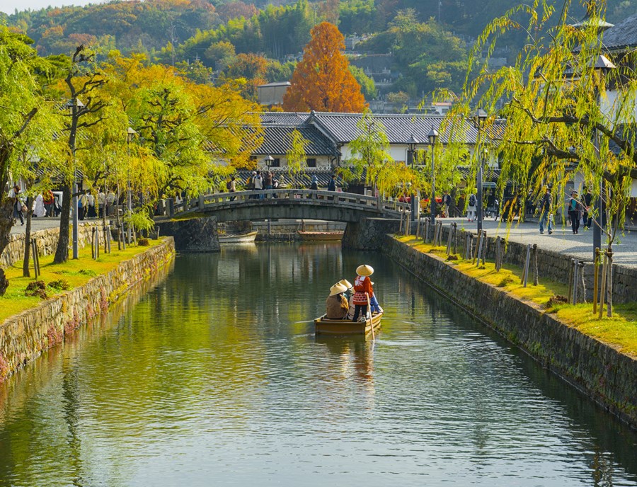 Canal Lined Scenery Of Kurashiki Bikan Historical Quarter With A Sightseeing Boat Gliding Along The Water