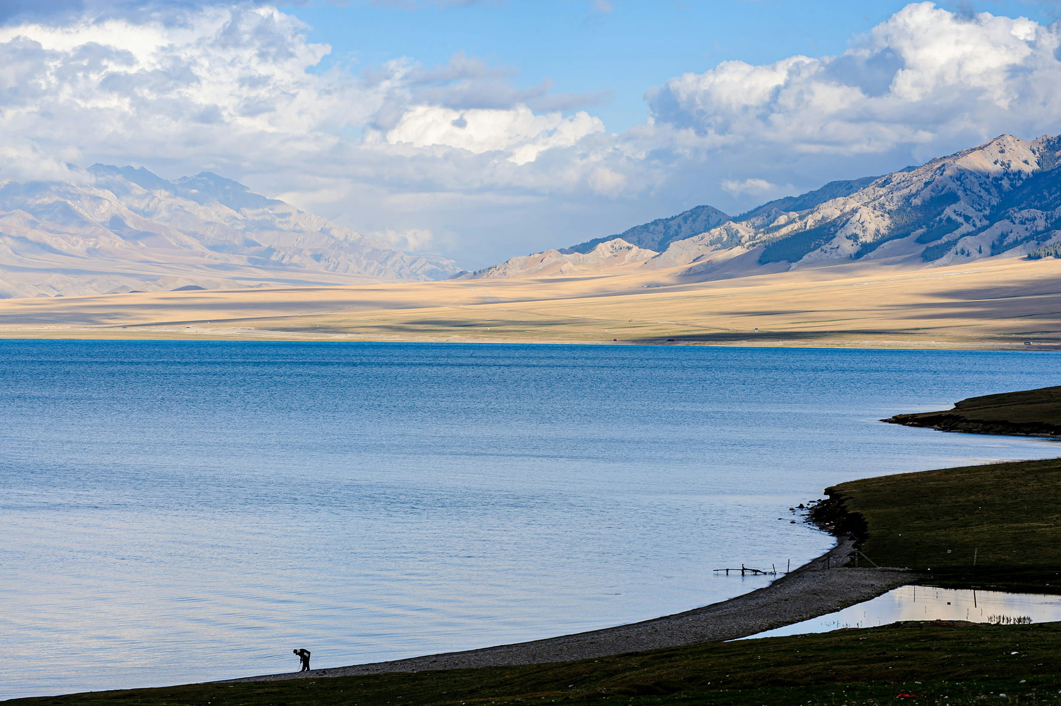 Take In The Brilliant Blue Waters Of Sayram Lake, Surrounded By The Mountains And Grasslands Of Xinjiang