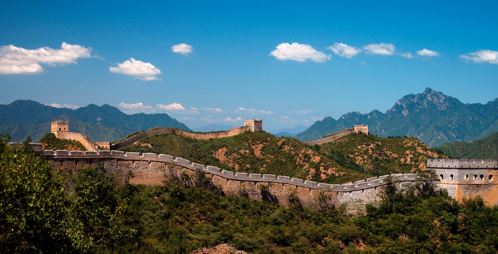 Walk along the ancient Great Wall with mountain views stretching beyond the horizon