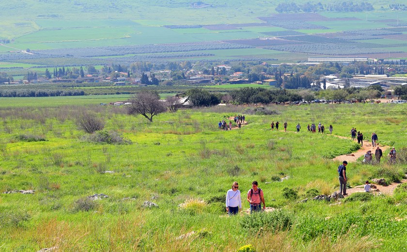 Hike along a trail through green meadows at Mount Arbel