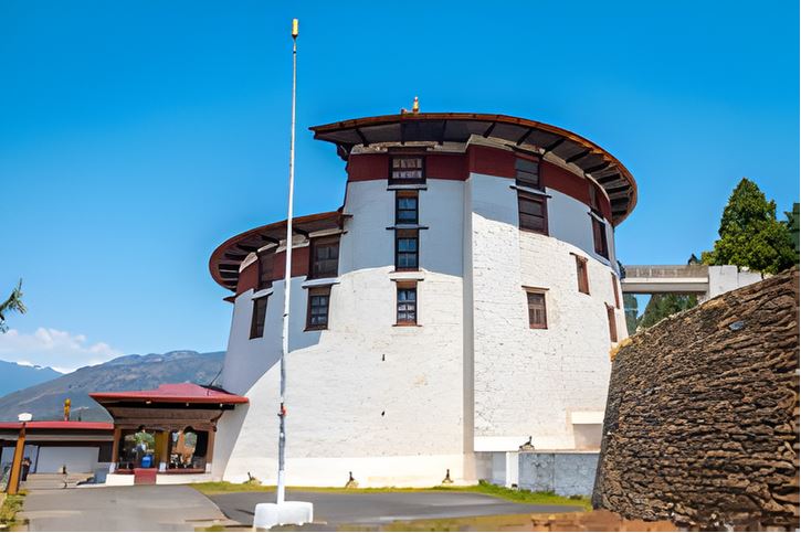 Exterior view of the National Museum of Bhutan (Ta Dzong) in Paro, a historic circular fortress set on a hillside overlooking the valley, showcasing traditional Bhutanese
