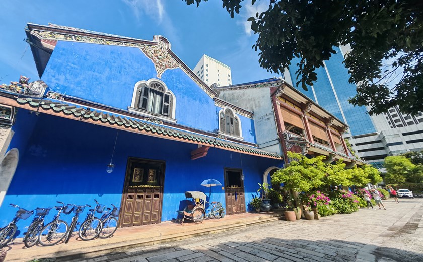A bright blue heritage building in George Town, Penang, with cobblestone street in front.